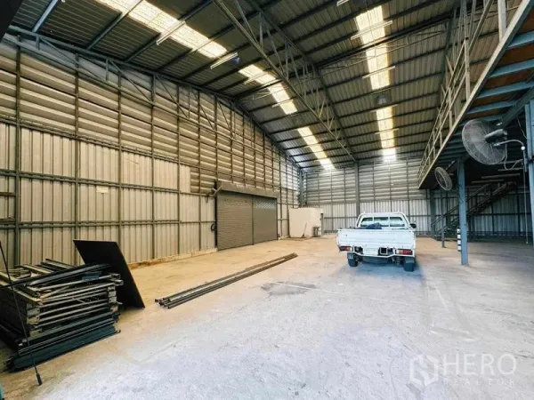 Warehouse for rent in Din Daeng, Bangkok - Spacious high-ceiling warehouse interior with skylights and a pickup truck.