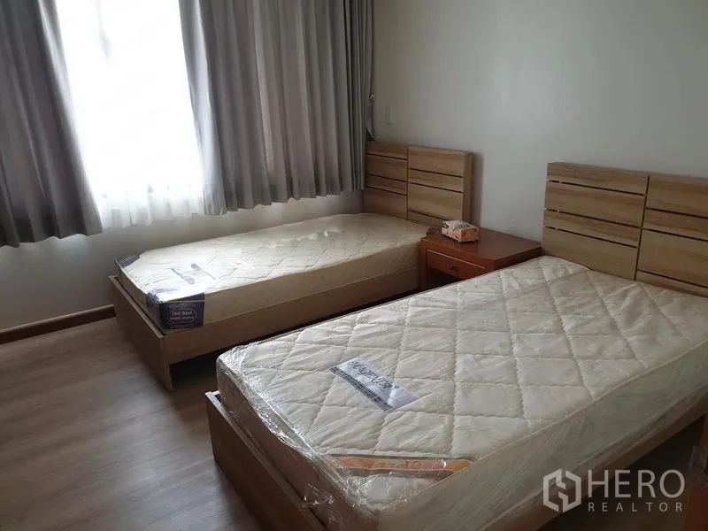 Condominium for rent in Watthana, Bangkok - Twin bedroom with two single beds, bedside table and window with curtains.