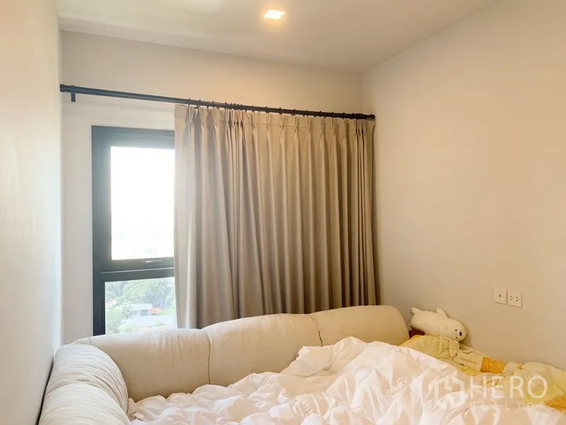 Condominium for sale in Suan Luang, Bangkok - Cozy bedroom with large window, blackout curtains and soft bed.