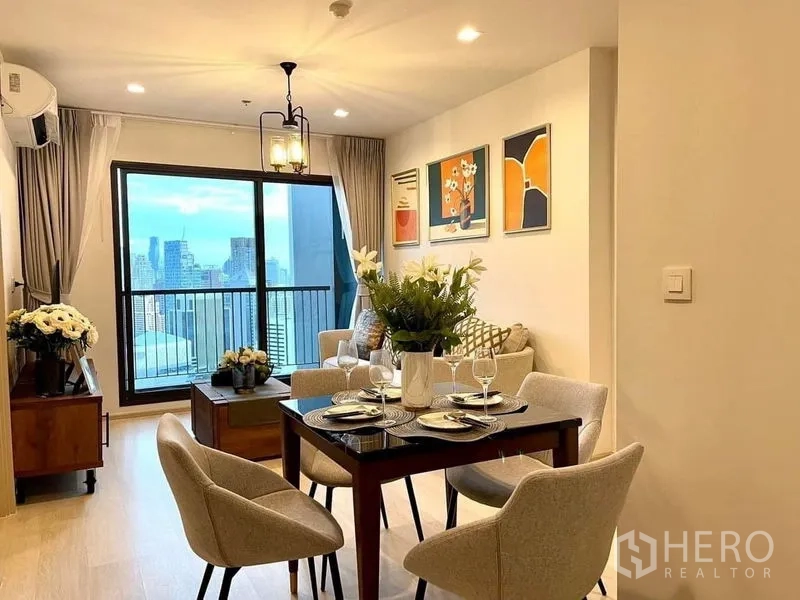 Condominium for rent in Pathum Wan, Bangkok - Dining table set for four beside the balcony with skyline views and modern wall art.