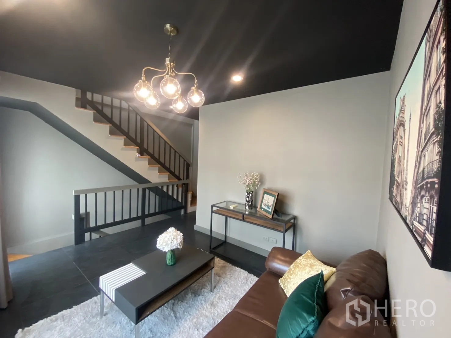 Townhouse for rent in Bang Kapi, Bangkok - Second-floor sitting area beside staircase with pendant chandelier.