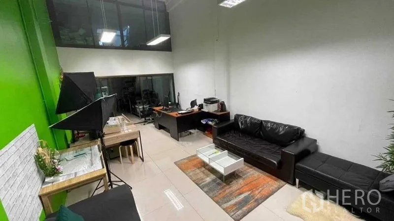 店屋 出租在Khlong Toei, Bangkok - 开放式工作区，带会客沙发、办公桌和绿色强调墙。