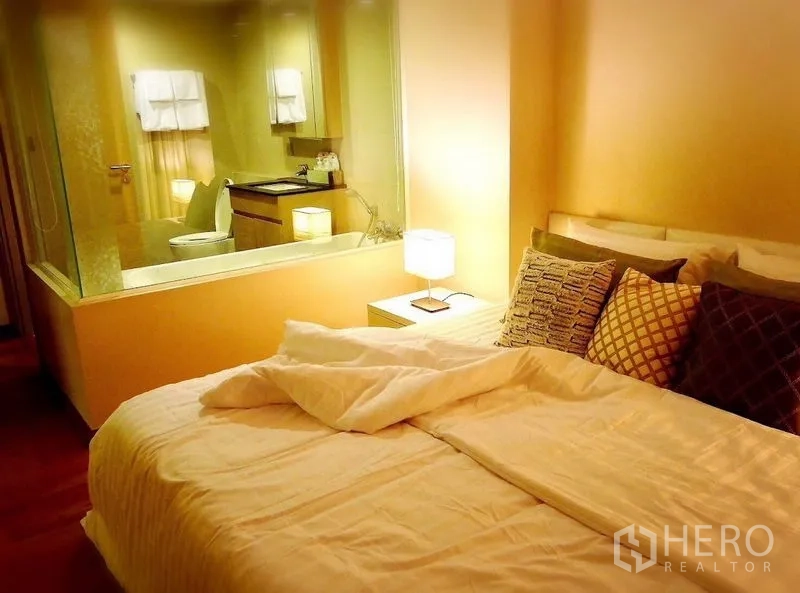 公寓 出售在Watthana, Bangkok - 卧室与浴室以玻璃隔断相连，床头灯与靠垫。