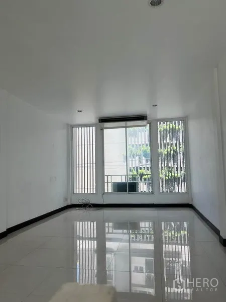 อาคารพาณิชย์ ให้เช่าในKhlong Toei, Bangkok - ห้องชั้นบนสว่าง พื้นกระเบื้องสีขาว หน้าต่างสูง พร้อมประตูบานเลื่อนไปยังระเบียงเล็ก