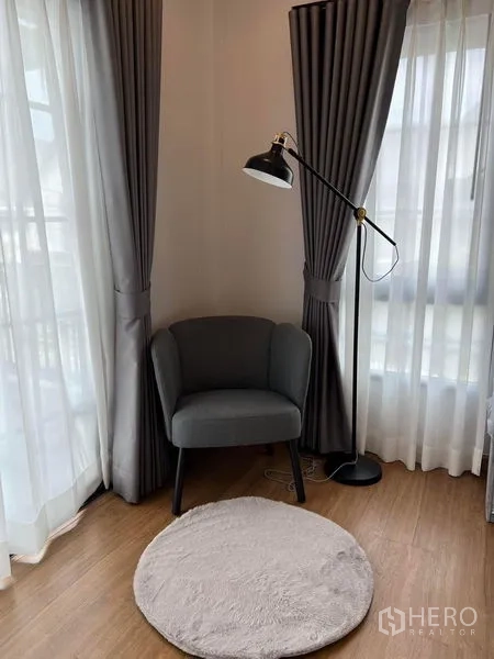 Detached House for rent in Bang Phli, Samut Prakan - Cozy reading nook with grey armchair, floor lamp and sheer drapes in the corner.