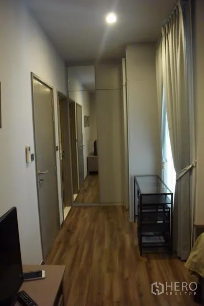 Condominium for rent in Watthana, Bangkok - Hallway featuring a mirrored wardrobe, curtain-lined window and wood flooring.