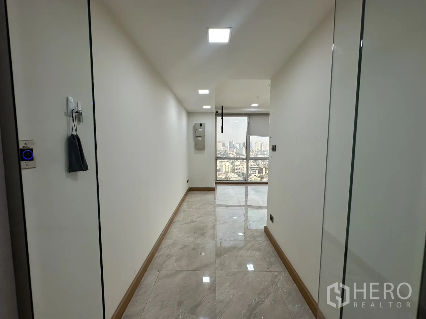 Office Space for rent - Bright corridor entry with glossy tiles leading to an office and skyline view.