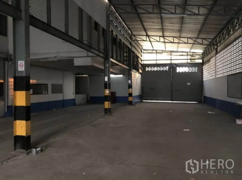 货栈 出租在Bang Phli, Samut Prakan - 室内装卸区，宽大双扇门与黄黑警示柱。