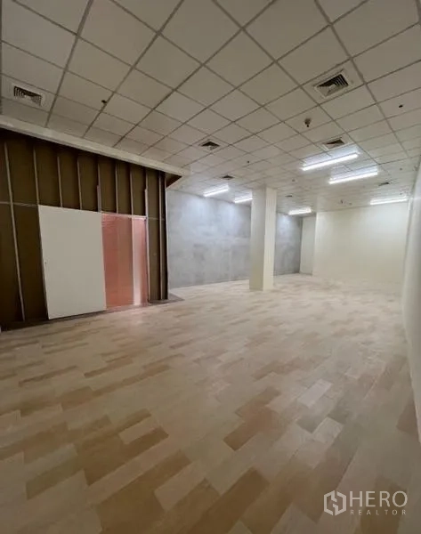 零售空间 出租在Watthana, Bangkok - 宽阔店内，网格吊顶、LED灯带及前方的板式隔断。