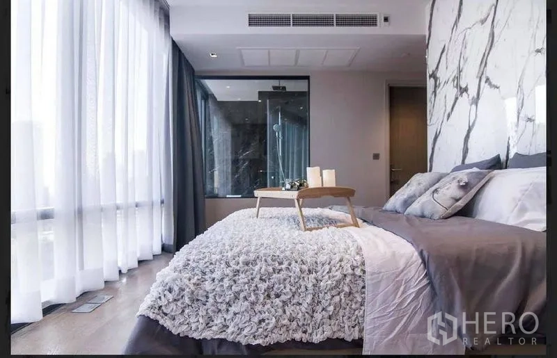 คอนโด ให้เช่าในBang Rak, Bangkok - ห้องนอนมาสเตอร์ ผนังลายหินอ่อน ชุดเครื่องนอนฟูฟ่อง ห้องอาบน้ำกระจก และม่านโปร่งรอบด้าน