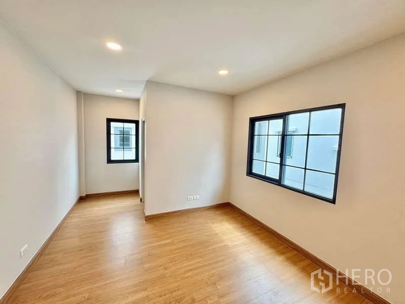 Detached House for sale in Bang Phli, Samut Prakan - Cozy bedroom with wood floors and twin windows.