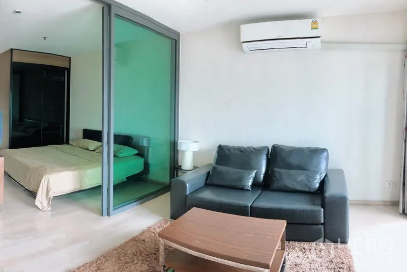 公寓 出租在Khlong Toei, Bangkok - Noble Remix 公寓客厅，皮沙发与茶几，玻璃推拉门分隔卧室，墙挂空调