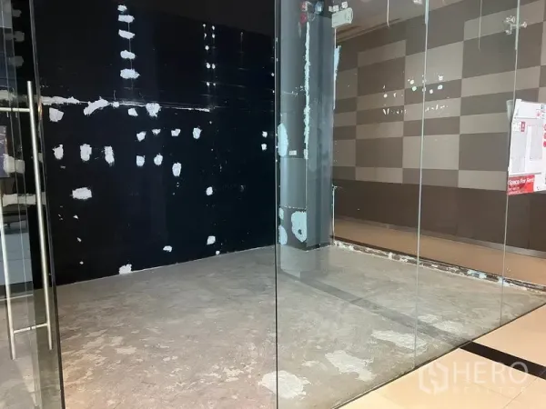零售空间 出租在Watthana, Bangkok - 透过透明玻璃可见紧凑零售空间，黑色强调墙，外侧为光洁的商场地砖。