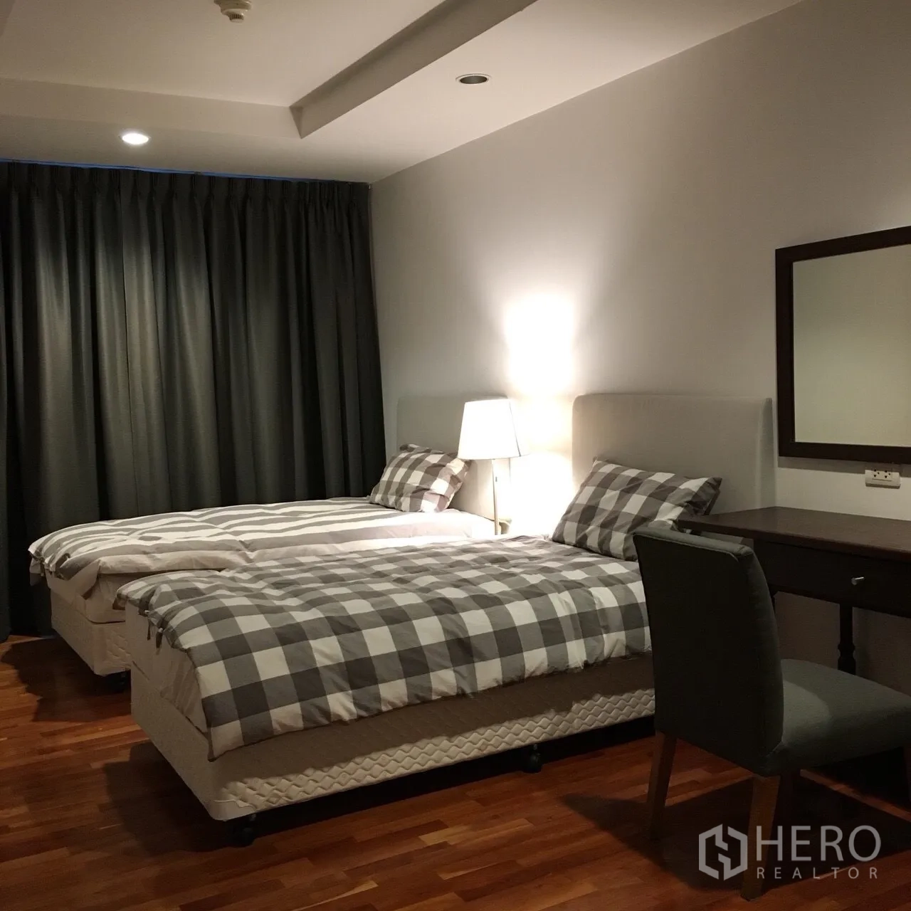 Condominium for rent in Watthana, Bangkok - Second bedroom with twin beds, bedside lamp, blackout curtains, and a work desk.