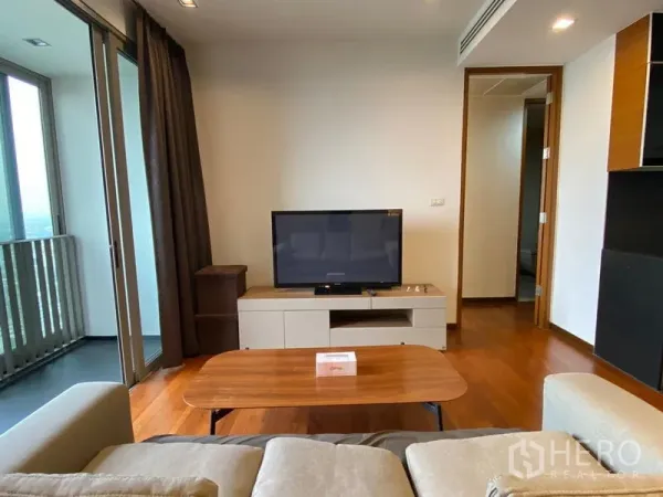 公寓 出租 - 舒适起居区，电视柜与茶几，滑门连接半封闭阳台，旁有走廊通往卧室。