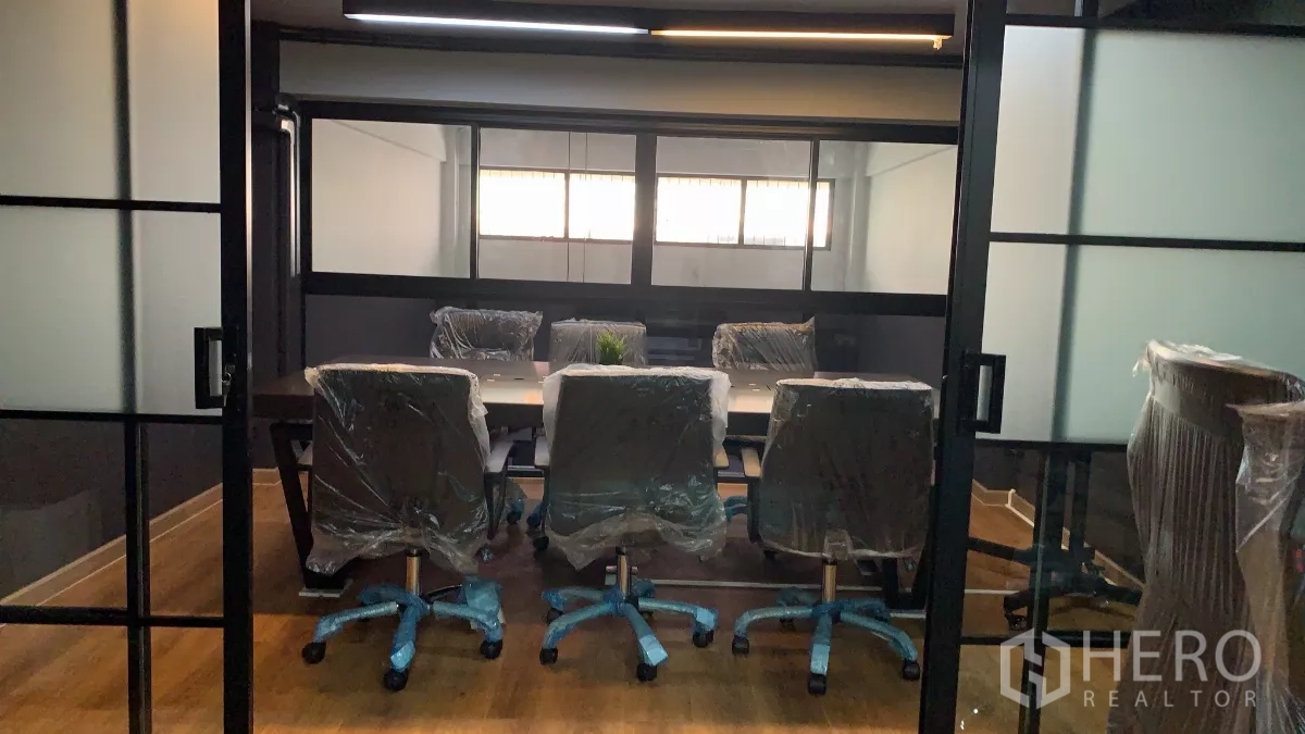 Home Office for rent in Pom Prap Sattru Phai, Bangkok - Conference room behind frosted sliding glass with a long table and wheeled chairs.