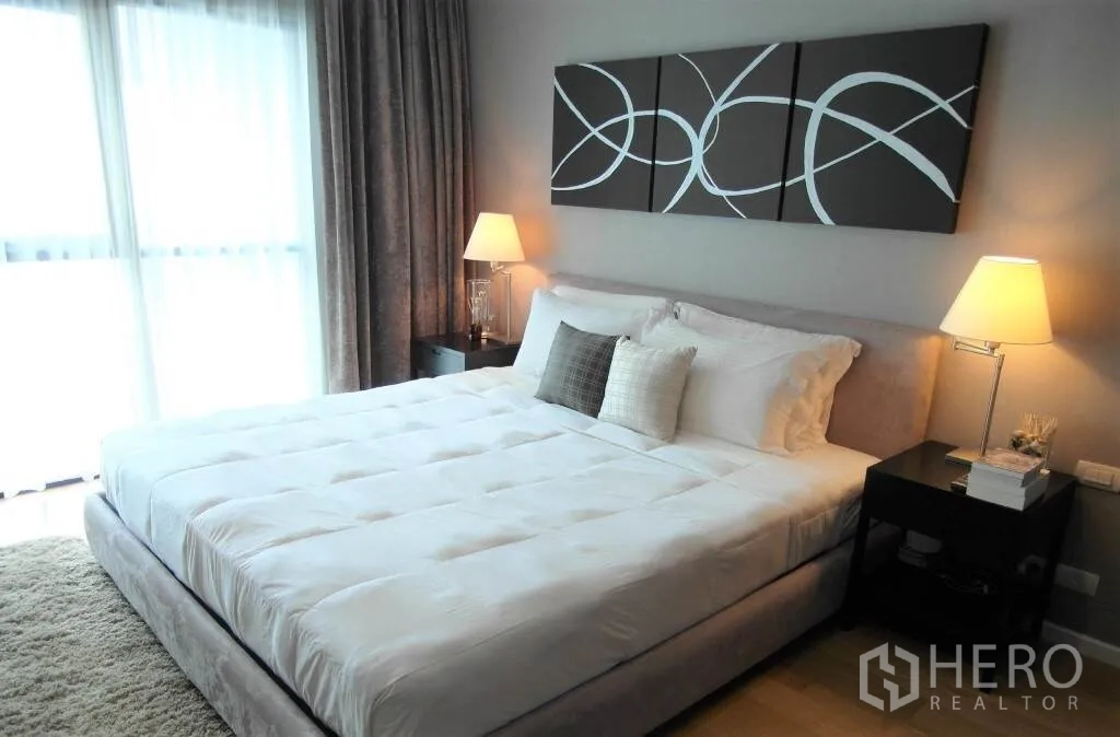 公寓 出租或出售在Sathon, Bangkok - 明亮主卧，配特大床、床头灯与落地窗帘。