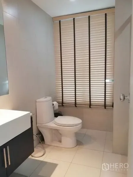 公寓 出租在Watthana, Bangkok - 现代浴室，设洗手台、坐便器及带百叶窗的窗户。