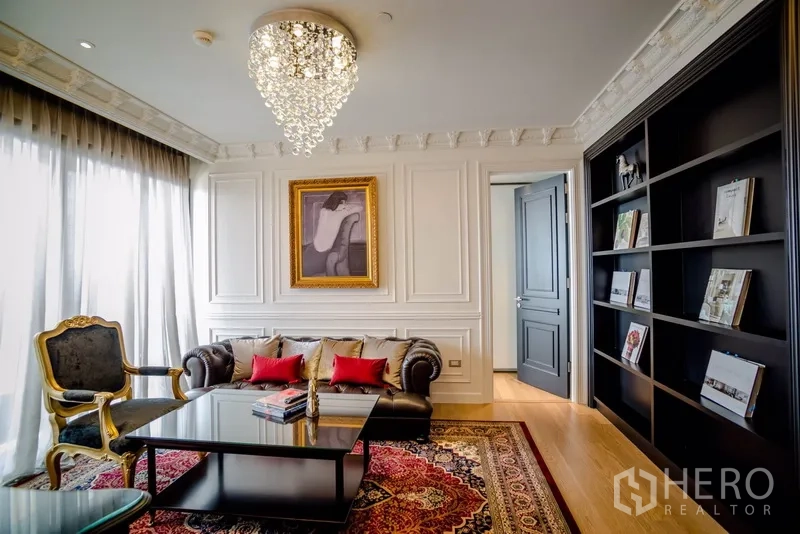 公寓 出租在Khlong Toei, Bangkok - 曼谷公寓客厅，水晶吊灯、皮沙发、精致墙面线条与黑色书柜，采光充足。