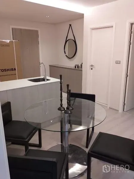 公寓 出租在Khlong Toei, Bangkok - 紧凑的厨房岛台带水槽，对向圆形餐桌与入户门，现代公寓格局。