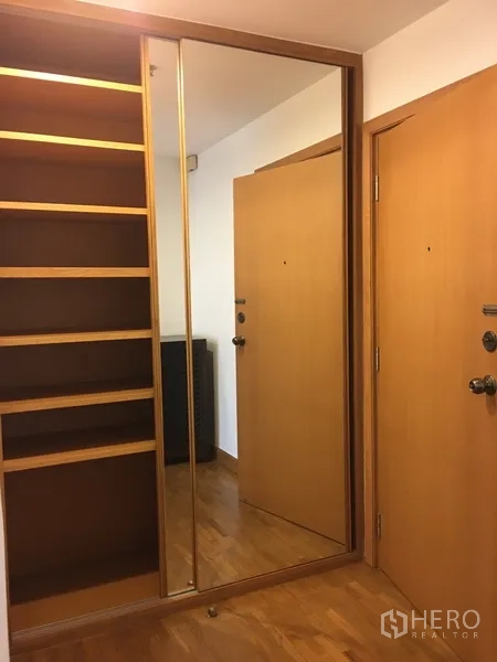 Condominium for rent in Pathum Wan, Bangkok - Entry foyer with built-in wooden shelving and full-height mirrored wardrobe doors.