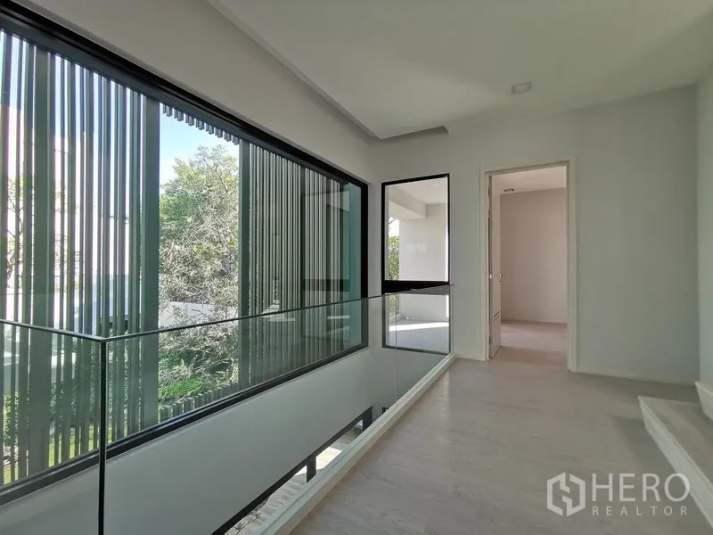 Detached House for sale in Saphan Sung, Bangkok - Bright mezzanine corridor with floor-to-ceiling windows and glass railing.