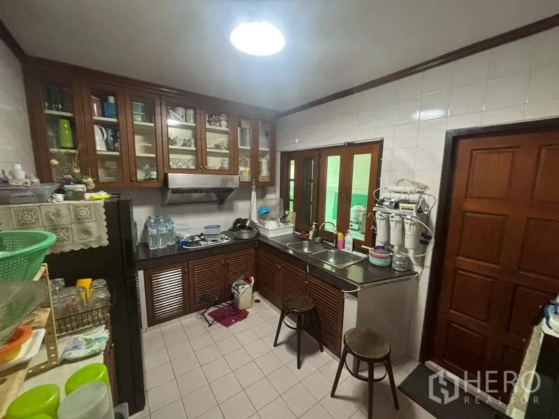 独栋房屋 for sale in Suan Luang, Bangkok - 实用厨房，瓷砖墙面、玻璃吊柜与双水槽。