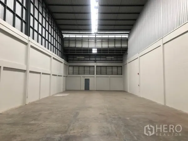 工厂 出租在Pak Kret, Nonthaburi - 高挑仓库，混凝土地面、钢结构屋顶与后方服务门。