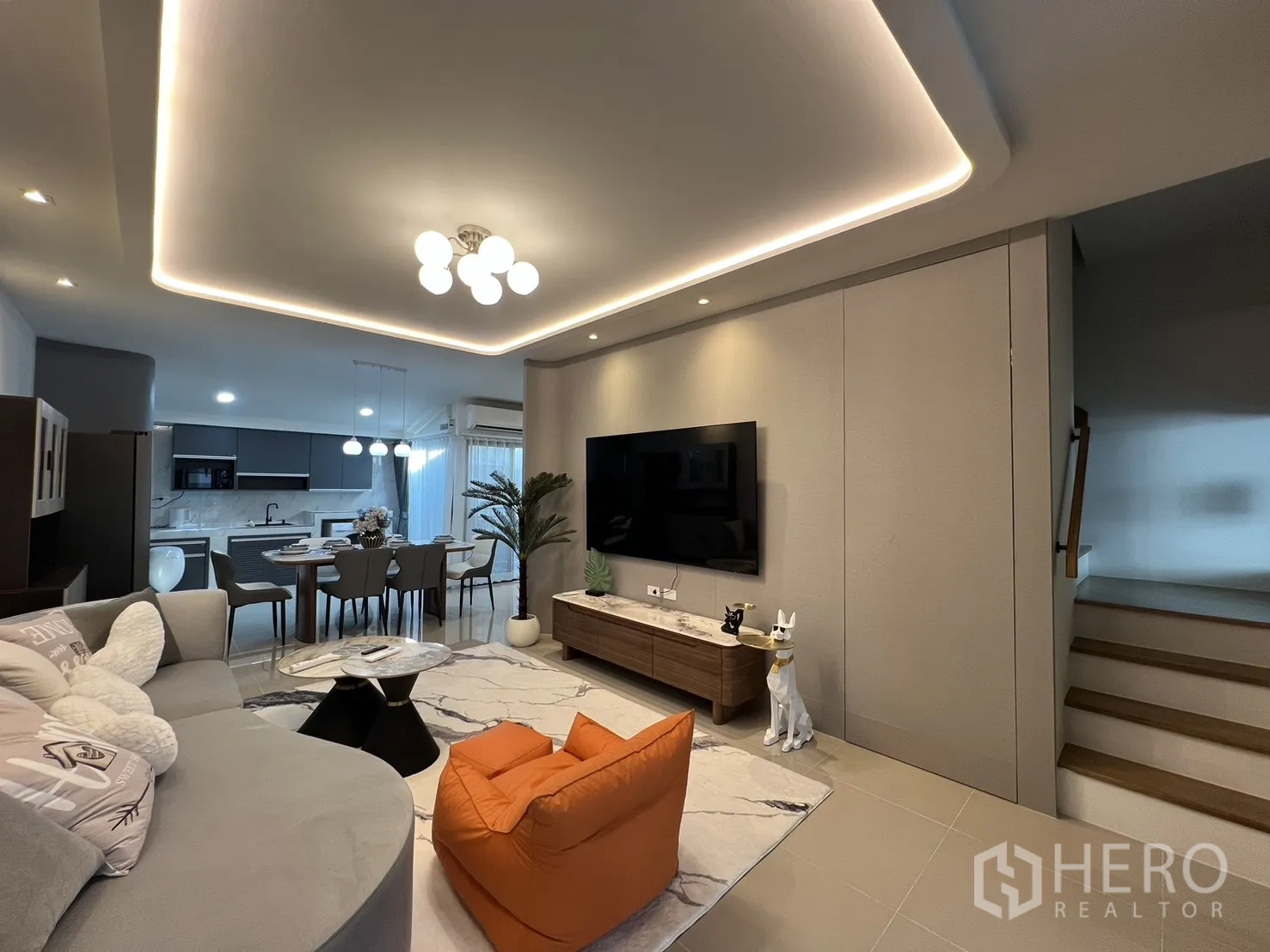Townhouse for rent in Bang Phli, Samut Prakan - Living room with large TV wall, stairs to the upper floor and an orange bean bag chair.