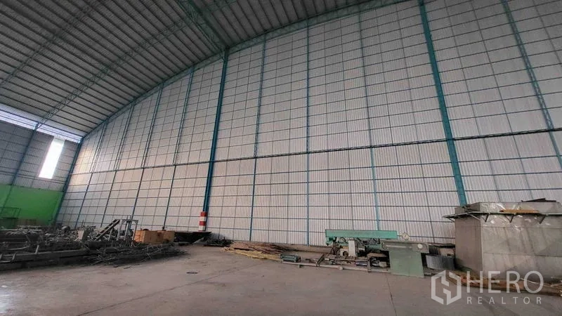 工厂 出租在Sai Noi, Nonthaburi - 厂房内部，高挑金属墙与屋顶，可见部分工业设备。