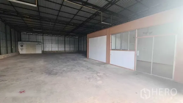 Warehouse for rent in Bang Kapi, Bangkok - Spacious storage bay with a built-in office partition and windows along one wall.