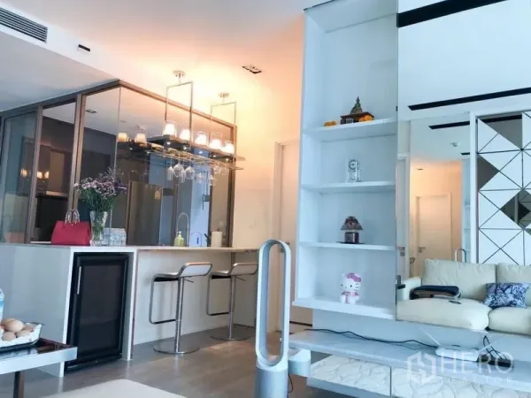 Condominium for rent or sale in Watthana, Bangkok - Open-plan kitchen and living area with bar stools, shelving and glass partitions.