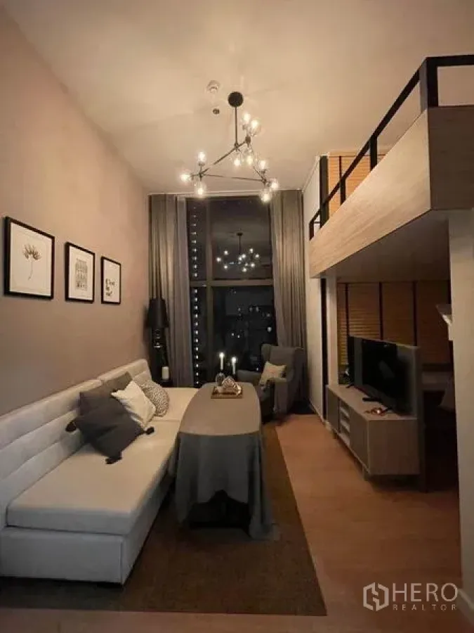 คอนโด ให้เช่าในRatchathewi, Bangkok - ห้องนั่งเล่นเพดานสูงสองชั้นพร้อมโคมระย้า โซฟา และชั้นลอยวางทีวี