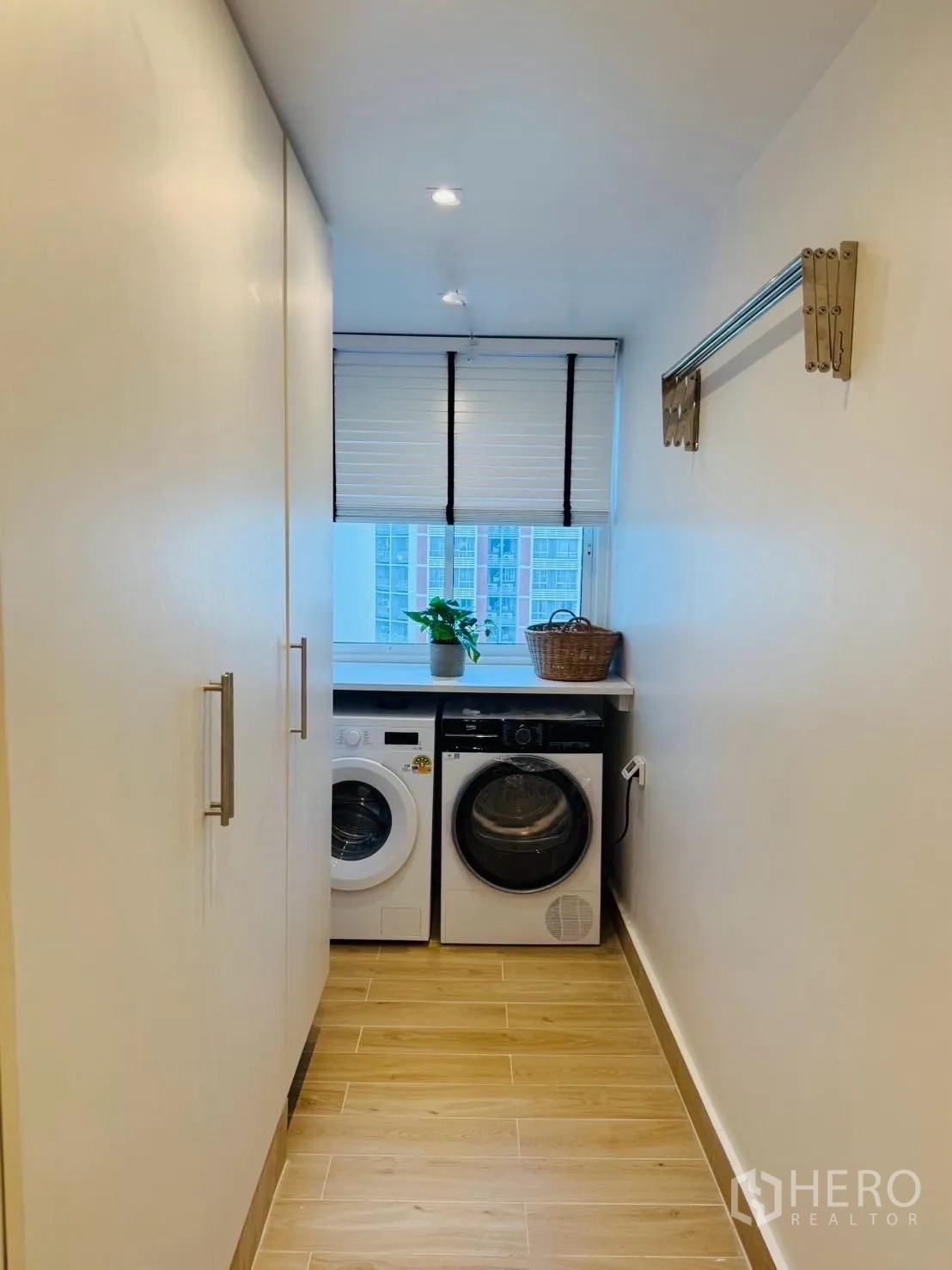 Condominium for rent or sale in Yan Nawa, Bangkok - Compact laundry room with washer and dryer under a counter, storage cupboards and a city-view window.
