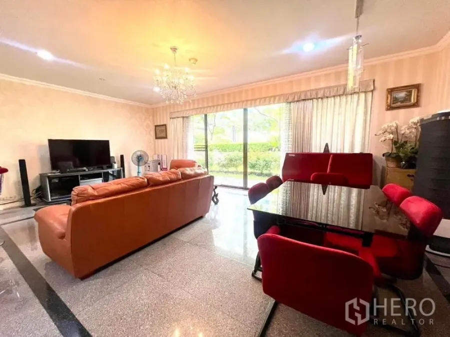 คอนโด ขายในPathum Wan, Bangkok - มุมพักผ่อนสว่างไสว โซฟาหนัง ทีวี และหน้าต่างกระจกสูงเต็มบานรับวิวสวน