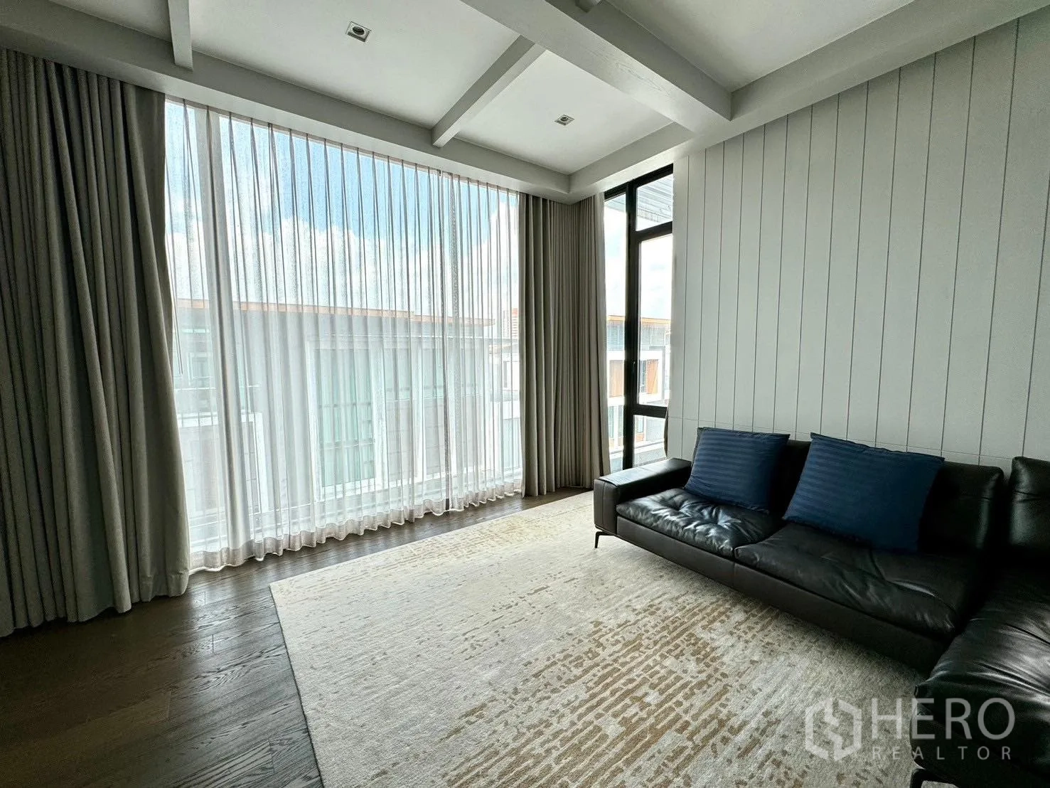 Detached House for rent or sale in Prawet, Bangkok - Sunlit living room with sheer curtains and leather sofa.