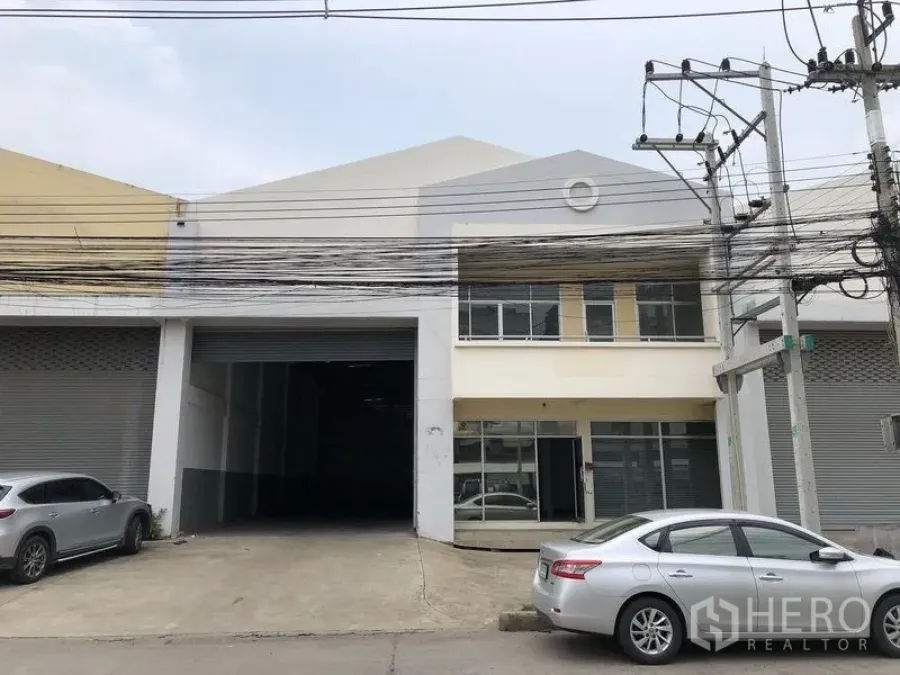 Factory for rent in Pathum Thani - Factory exterior in Khlong Luang, Pathum Thani with wide roller shutter, two-storey office and parking apron.