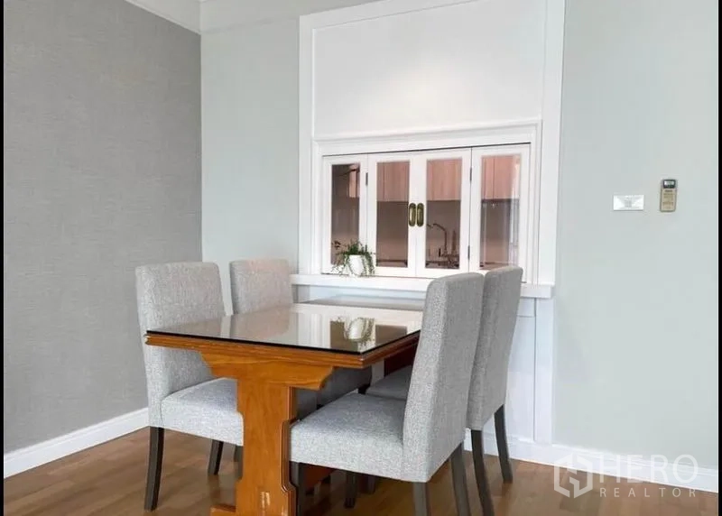 公寓 出租在Sathon, Bangkok - 餐区配玻璃台面餐桌与四把软包椅，旁有传菜窗。