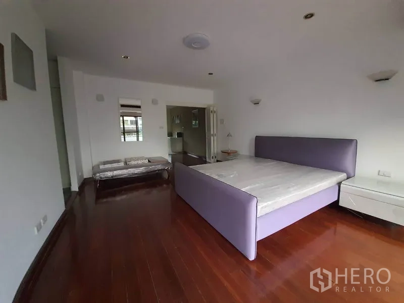 ทาวน์เฮาส์ ให้เช่าในKhlong Toei, Bangkok - ห้องนอนกว้าง พื้นไม้จริง เตียงกรอบสีม่วง และโต๊ะข้างเตียง