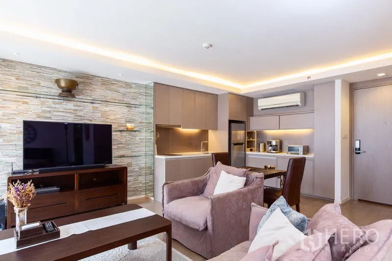 คอนโด ให้เช่าในWatthana, Bangkok - ห้องนั่งเล่นแบบโอเพ่นพลันพร้อมตู้วางทีวี ผนังหิน และครัวขนาดกะทัดรัด