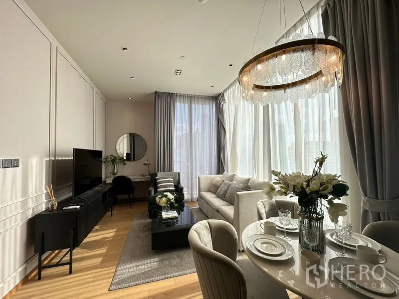Condominium for rent in Pathum Wan, Bangkok - Living room and dining corner with statement chandelier and TV cabinet.