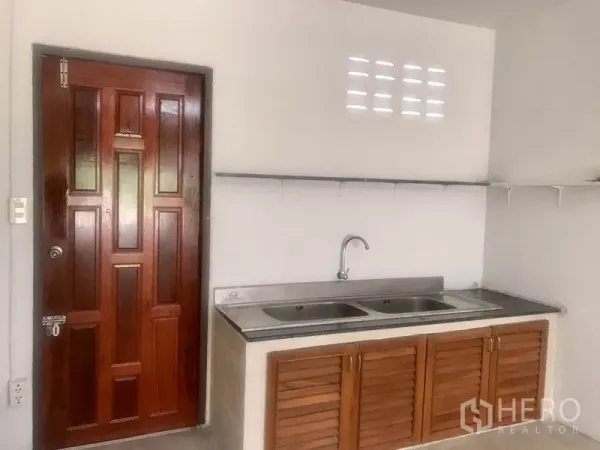 Warehouse for rent in Lam Luk Ka, Pathum Thani - Compact pantry with double stainless sink, wooden door and wall shelving.
