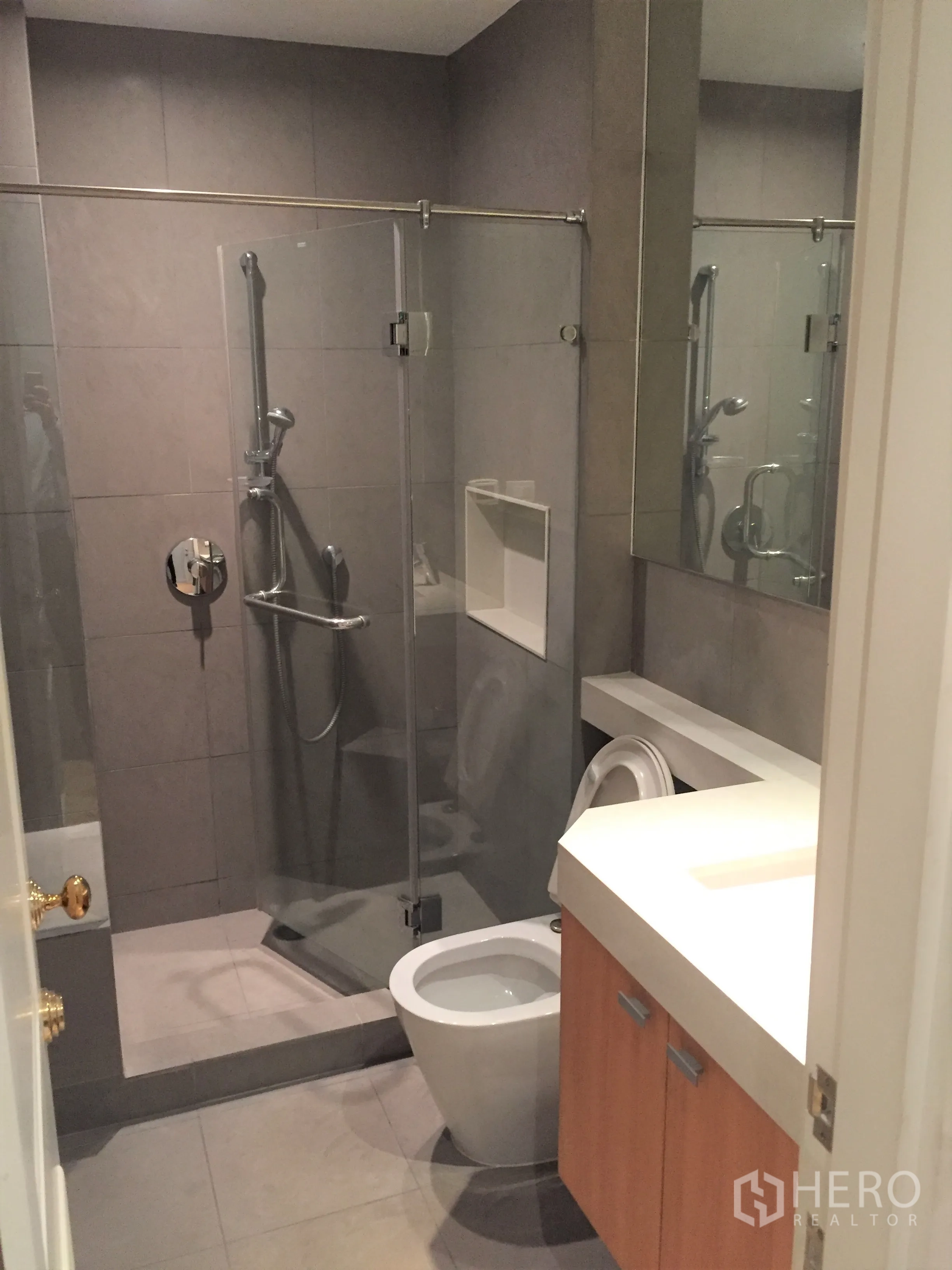 Condominium for rent or sale in Pathum Wan, Bangkok - Modern bathroom with glass-enclosed shower, wall-mounted fixtures and sleek vanity.