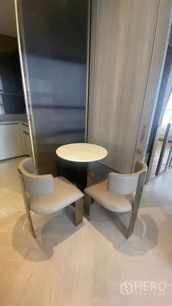 Condominium for rent - Close-up of round dining table with two upholstered chairs against a textured panel.