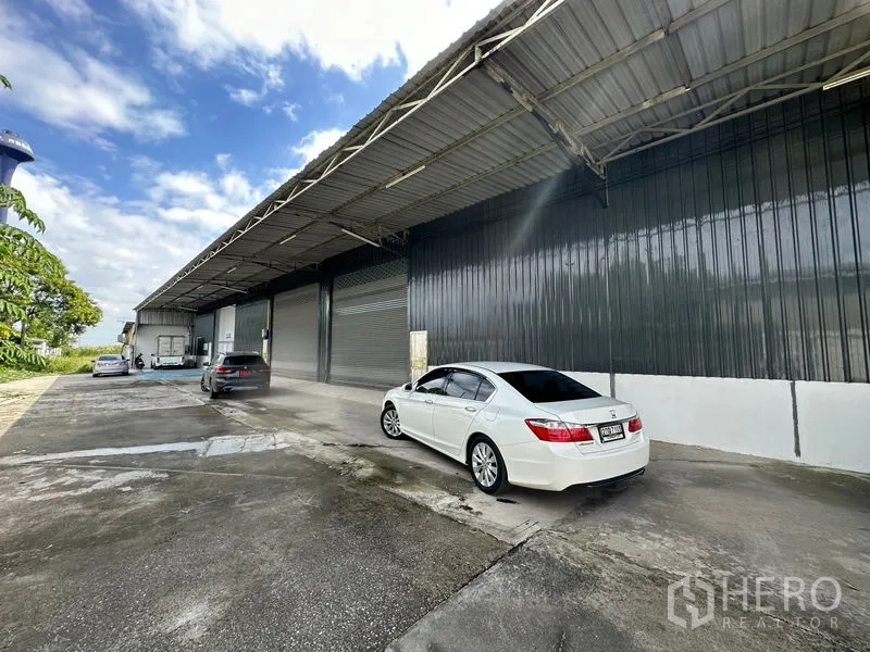 货栈 出租在Khlong Luang, Pathum Thani - 外立面配长雨棚、停车区及卷闸门，卡车进出便捷。