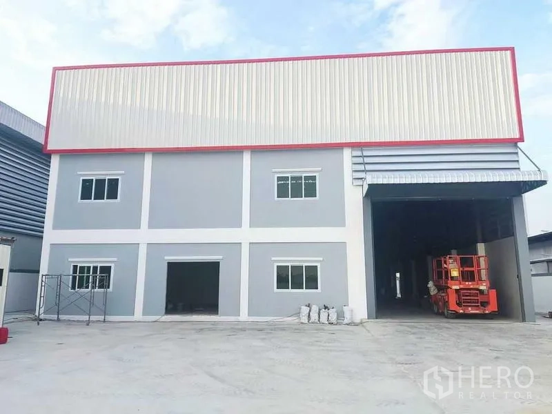 Factory for sale in Krathum Baen, Samut Sakhon - Two-storey factory facade with large roller door, covered loading bay, and concrete yard.