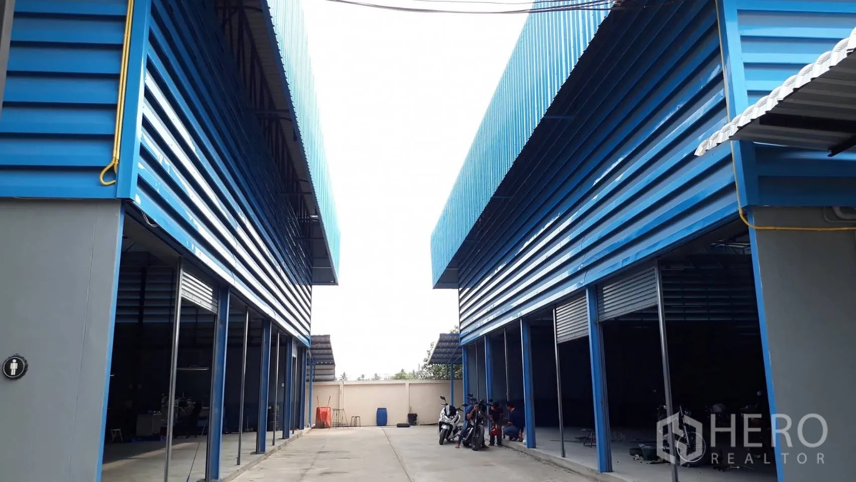 Warehouse for sale in Thung Khru, Bangkok - Two blue warehouse buildings facing each other across a central driveway.