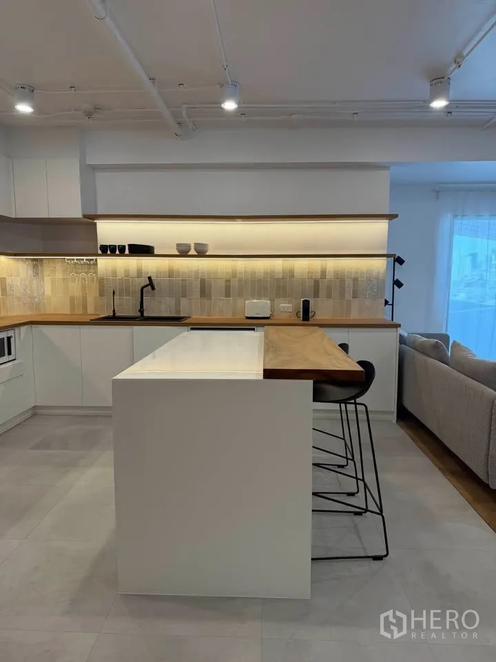 Condominium for rent in Watthana, Bangkok - Kitchen island with bar seating and full tiled backsplash view.