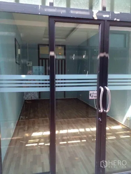 Shophouse for sale in Lam Luk Ka, Pathum Thani - Small room behind sliding glass door with wood-style flooring.