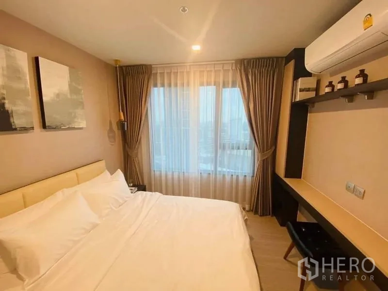 คอนโด ให้เช่า - ห้องนอนที่สองมีโต๊ะทำงาน ชั้นวางของ ผ้าม่านโปร่ง และเครื่องปรับอากาศ